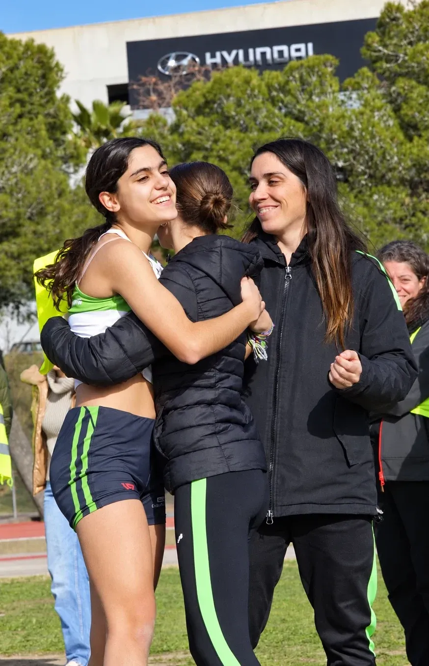 Atleta abrazándose con el equipo técnico y las familias después de una carrera